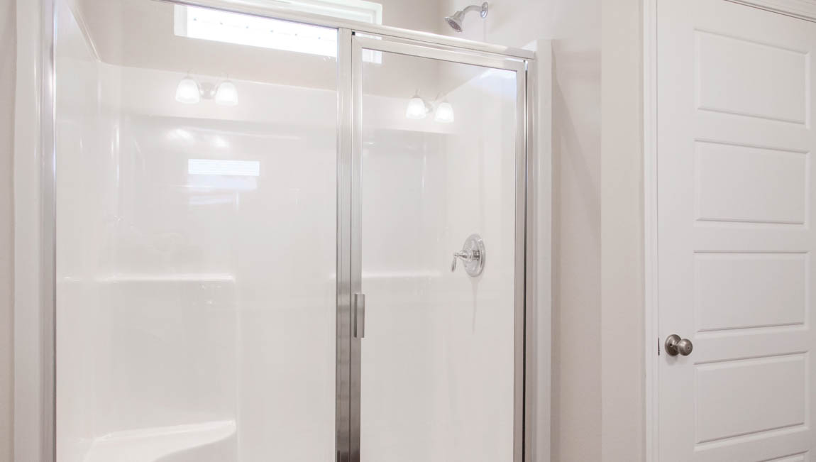 Large walk in shower with framed glass door and neutral walls in Hawkins Manor.