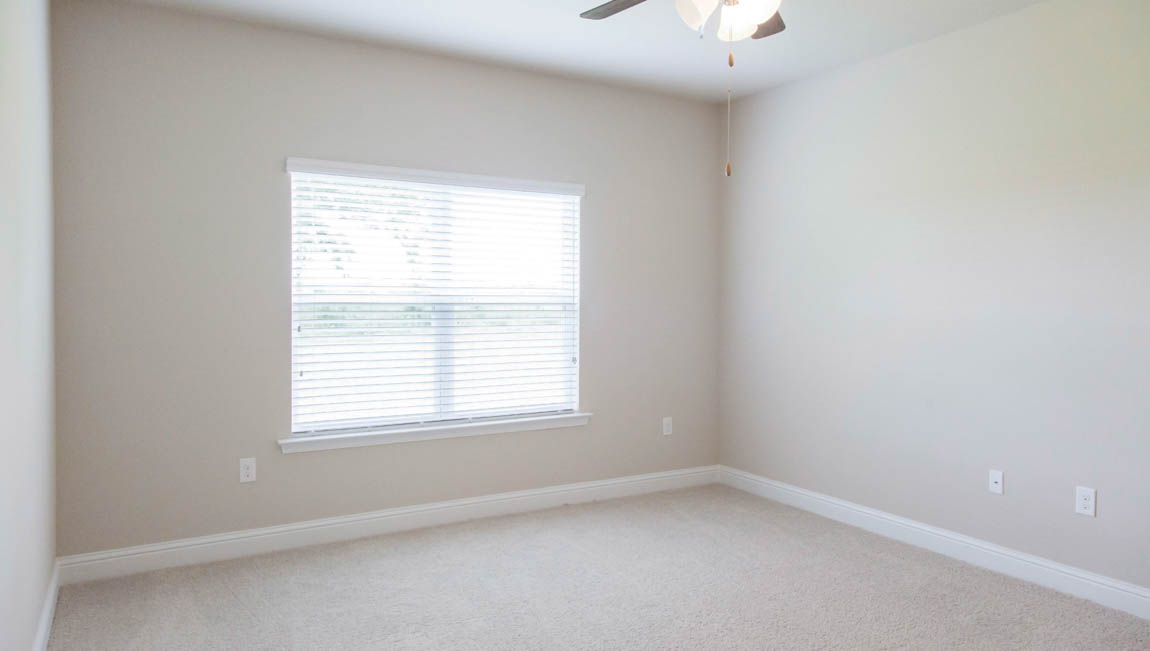 Primary bedroom with plush carpet and ceiling fan in a new construction D.R. Horton home.