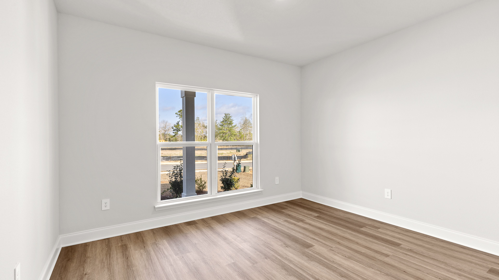 Light filled guest bedroom with white trim and luxury vinyl plank flooring in Hawkins Manor.
