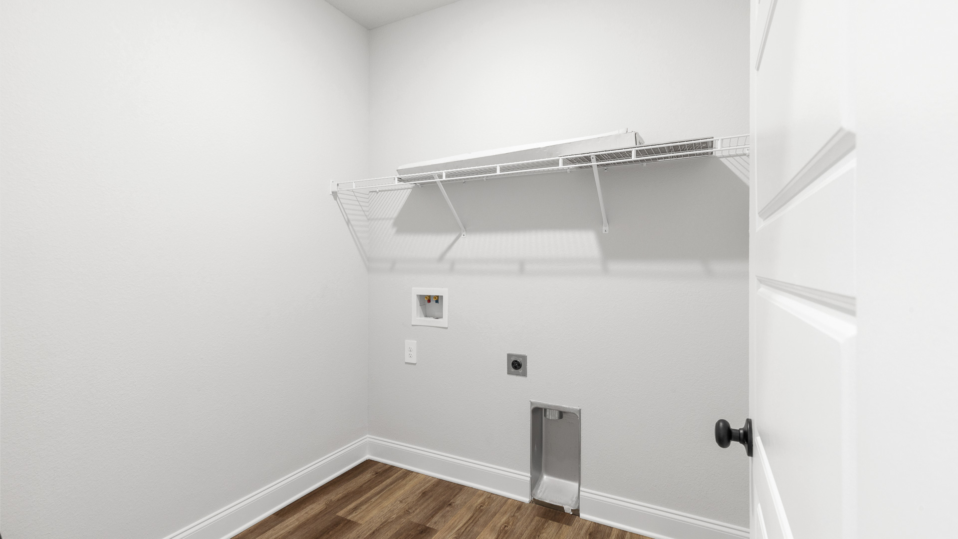 Functional laundry space with washer and dryer hookup and shelving for storage.