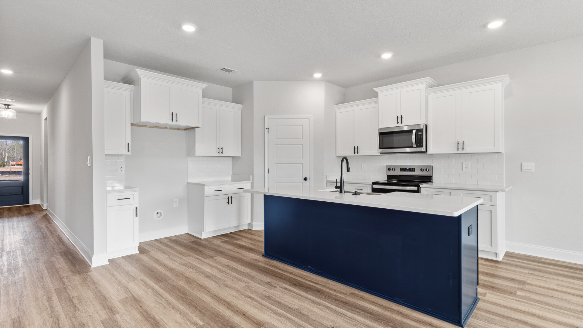 Open kitchen with large central island and white cabinets in a new home in Hawkins Manor.