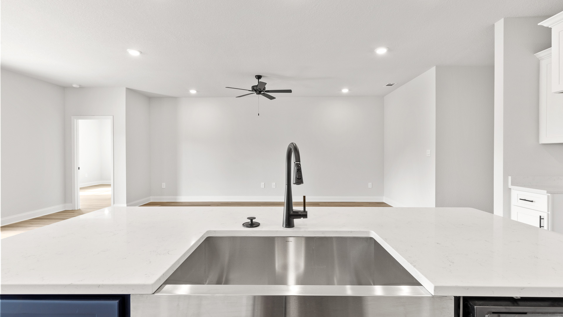 Large island with undermount stainless steel farmhouse sink looking into the living area.