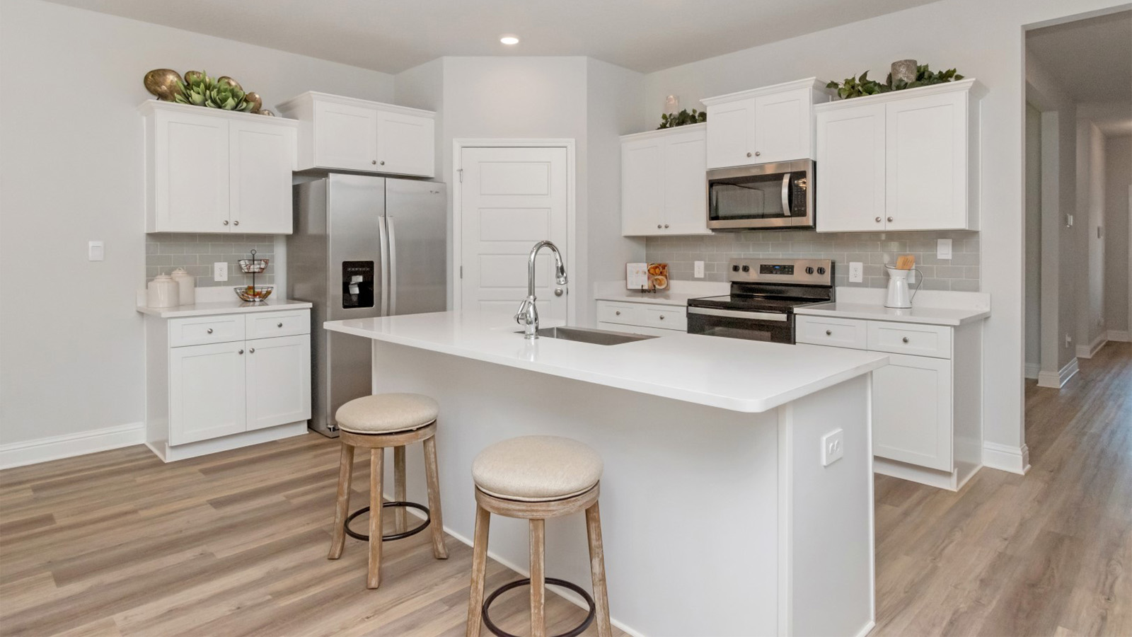 Spacious kitchen with white cabinets and stainless steel appliances in a new construction home built by D.R. Horton.