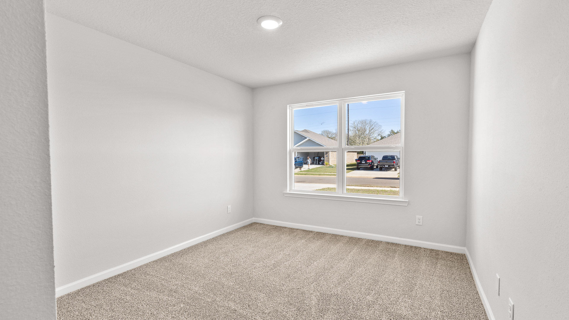 Carpeted well lit guest bedroom with large window in Semmes.