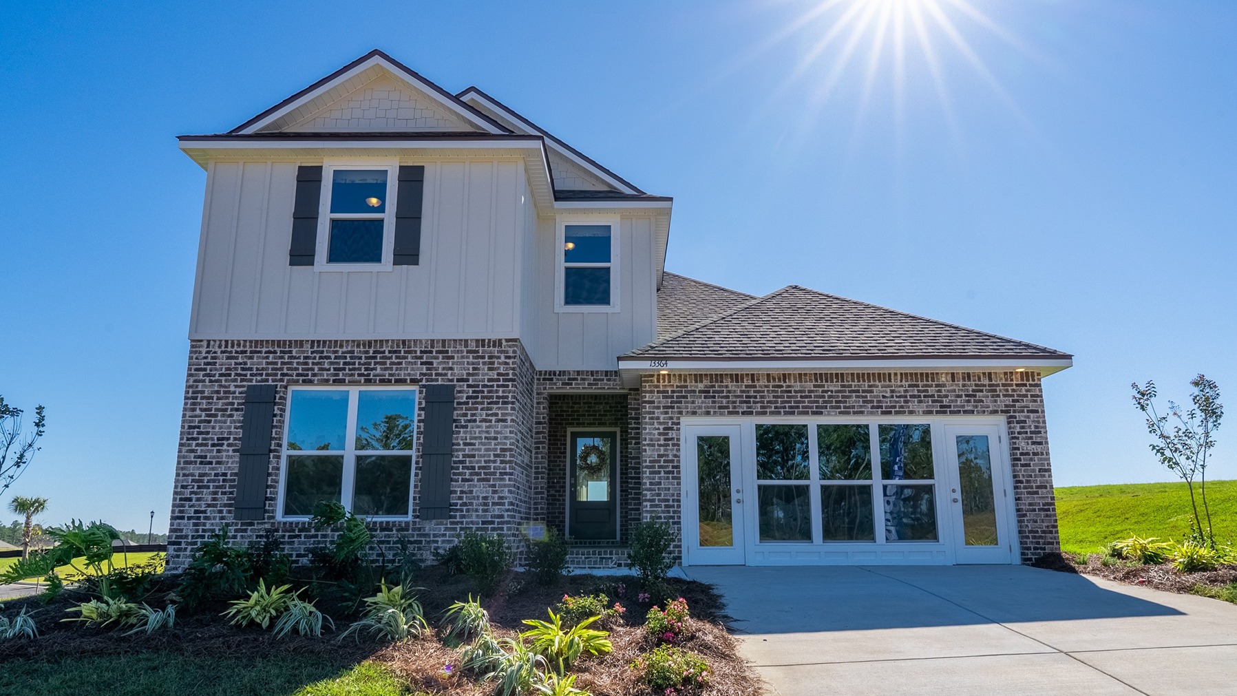 Two-story home with brick and board and batten exterior and a two-car garage.