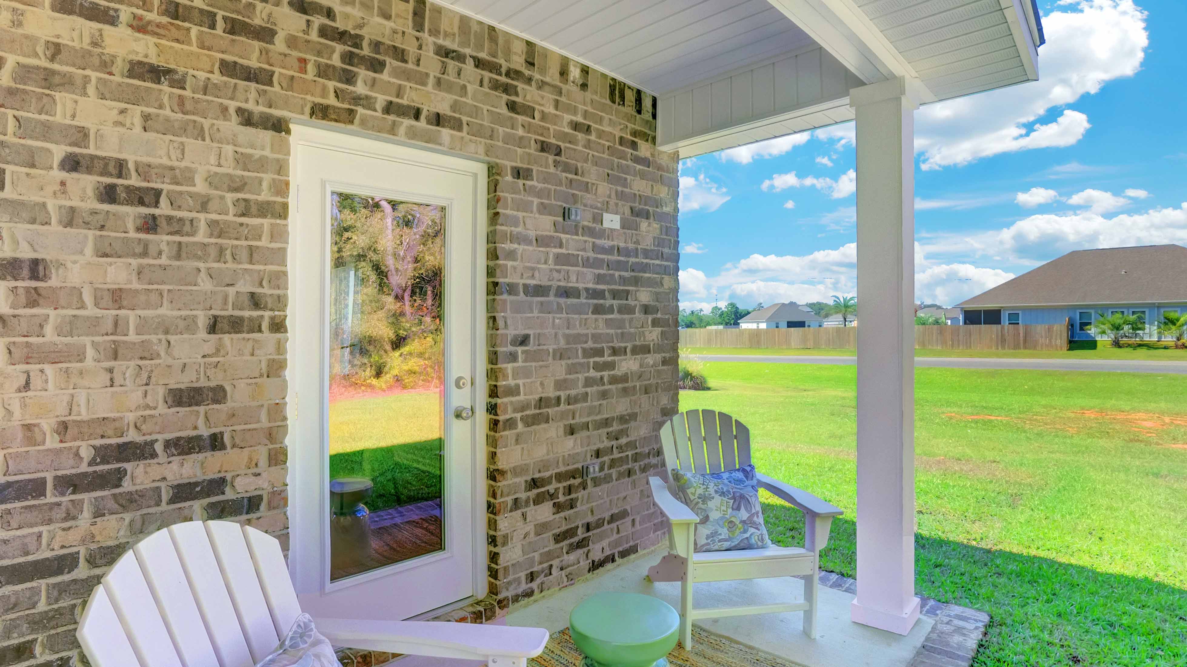 Back porch of new brick home with white column and nice yard.
