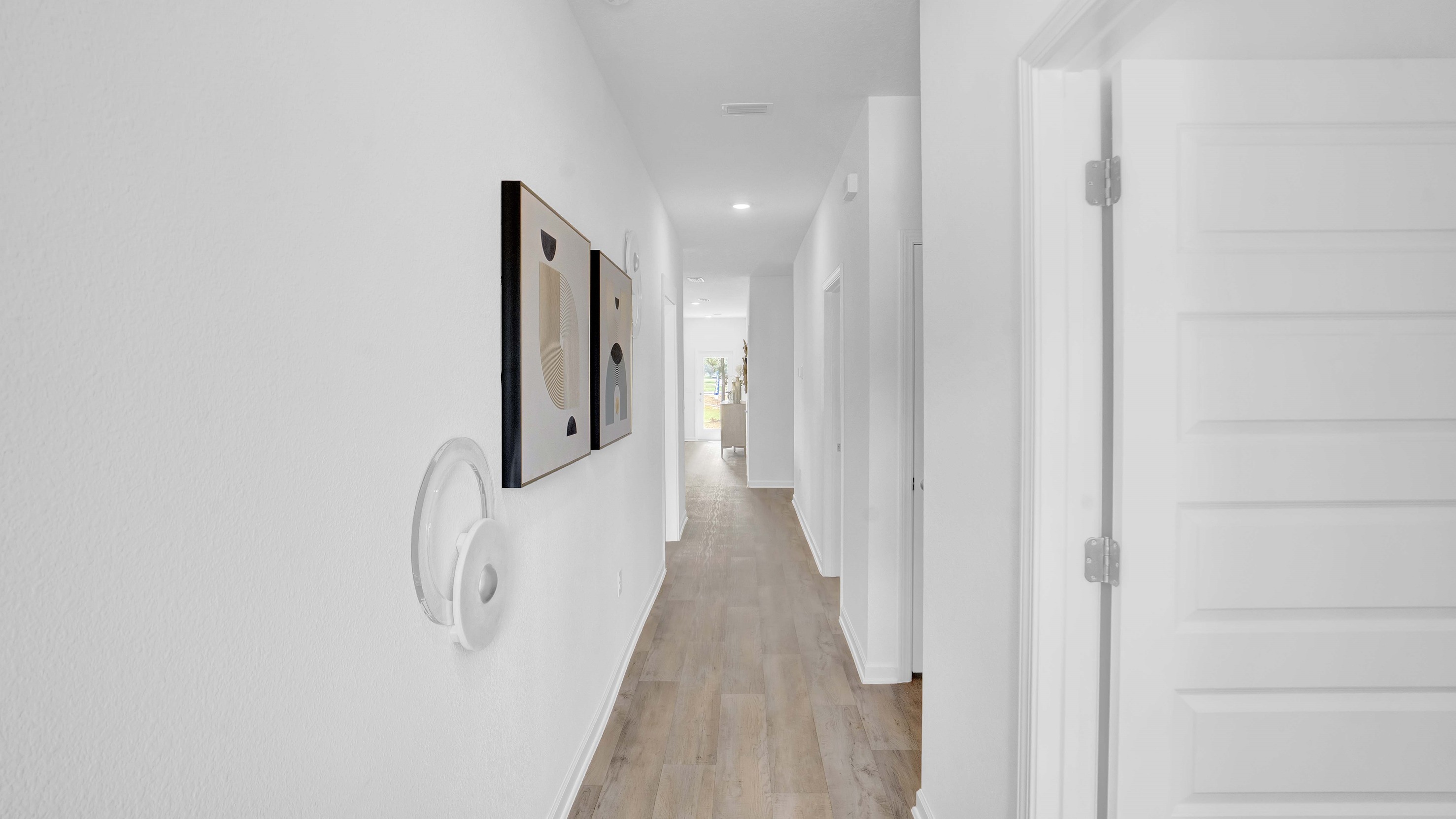 Foyer opens into bedrooms with white walls and art.