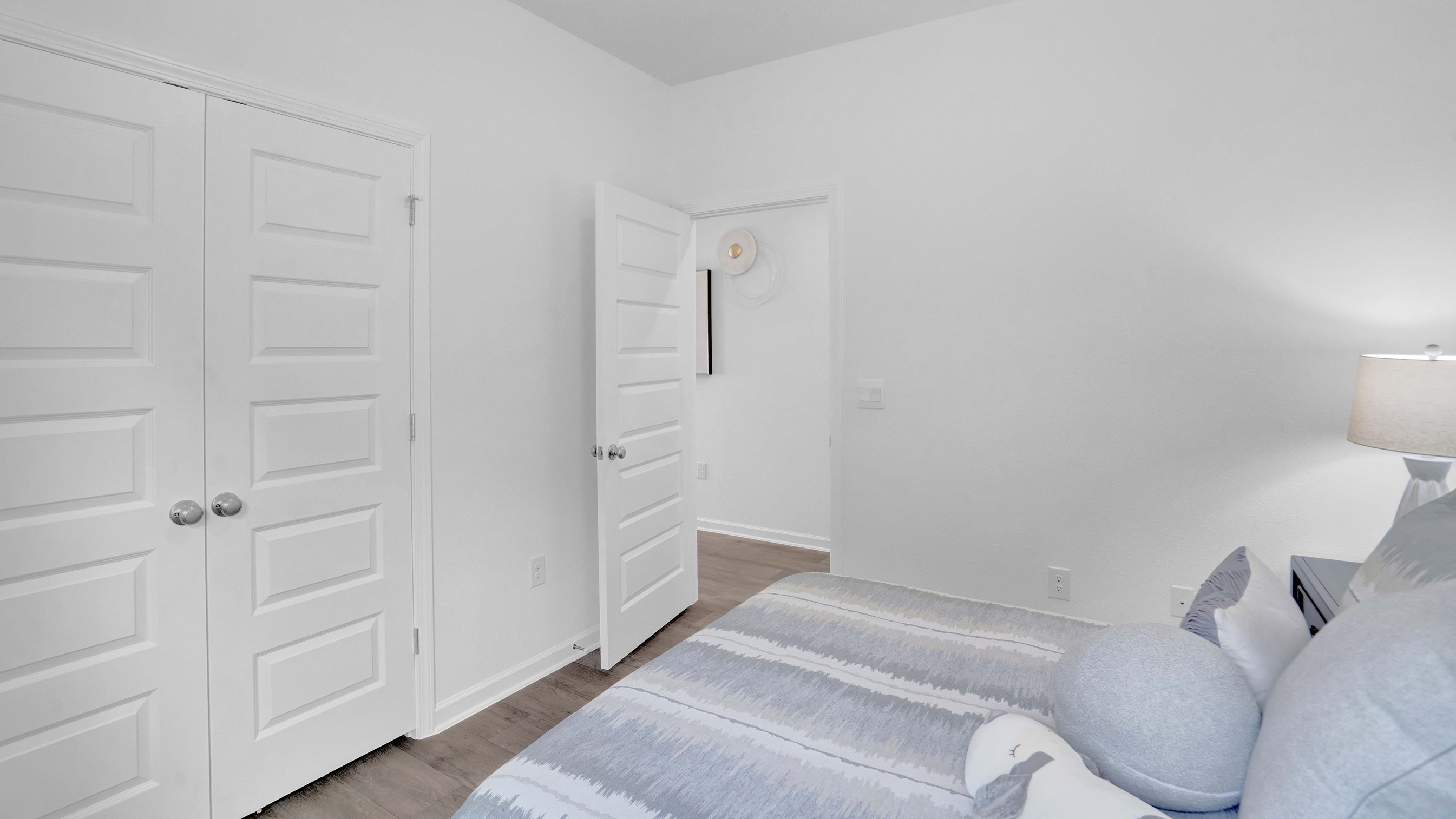 Bedroom with white walls with bed facing doorway.