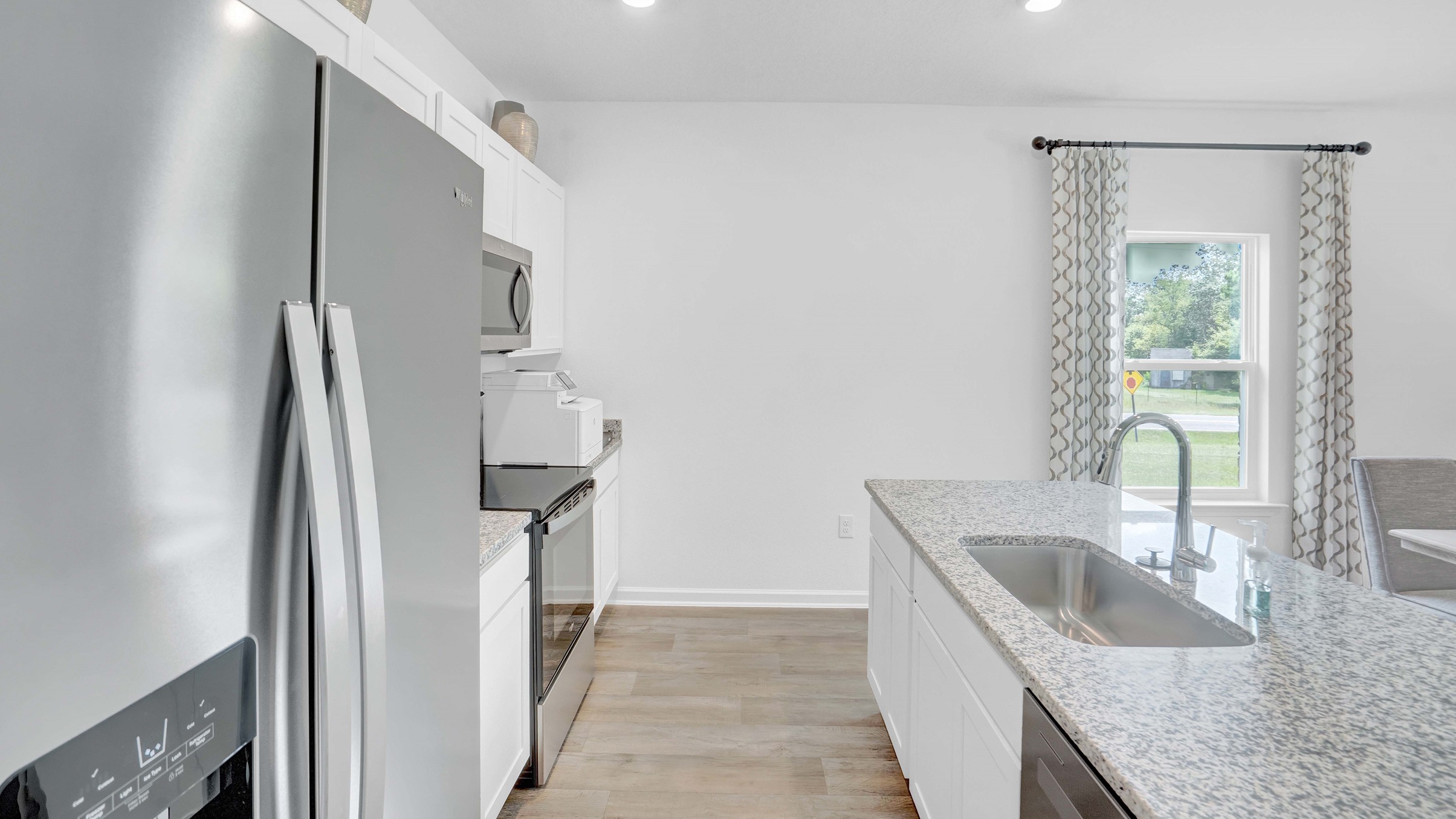 Kitchen with island, granite countertops, appliances from a side angle.