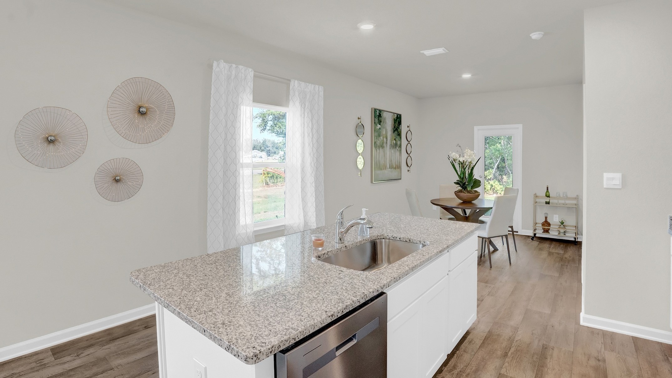 Kitchen island with sink looking out through the windows and art on walls.