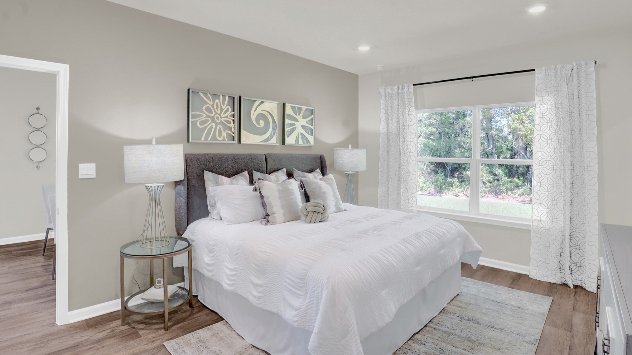 Bedroom with large bed, recessed lighting and windows showing natural light .