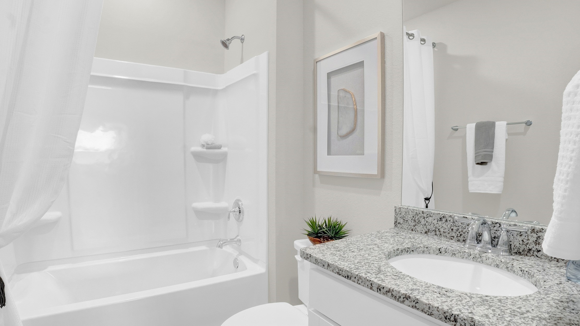 Secondary shower with tub and shower combination showing sink and countertop with mirror.