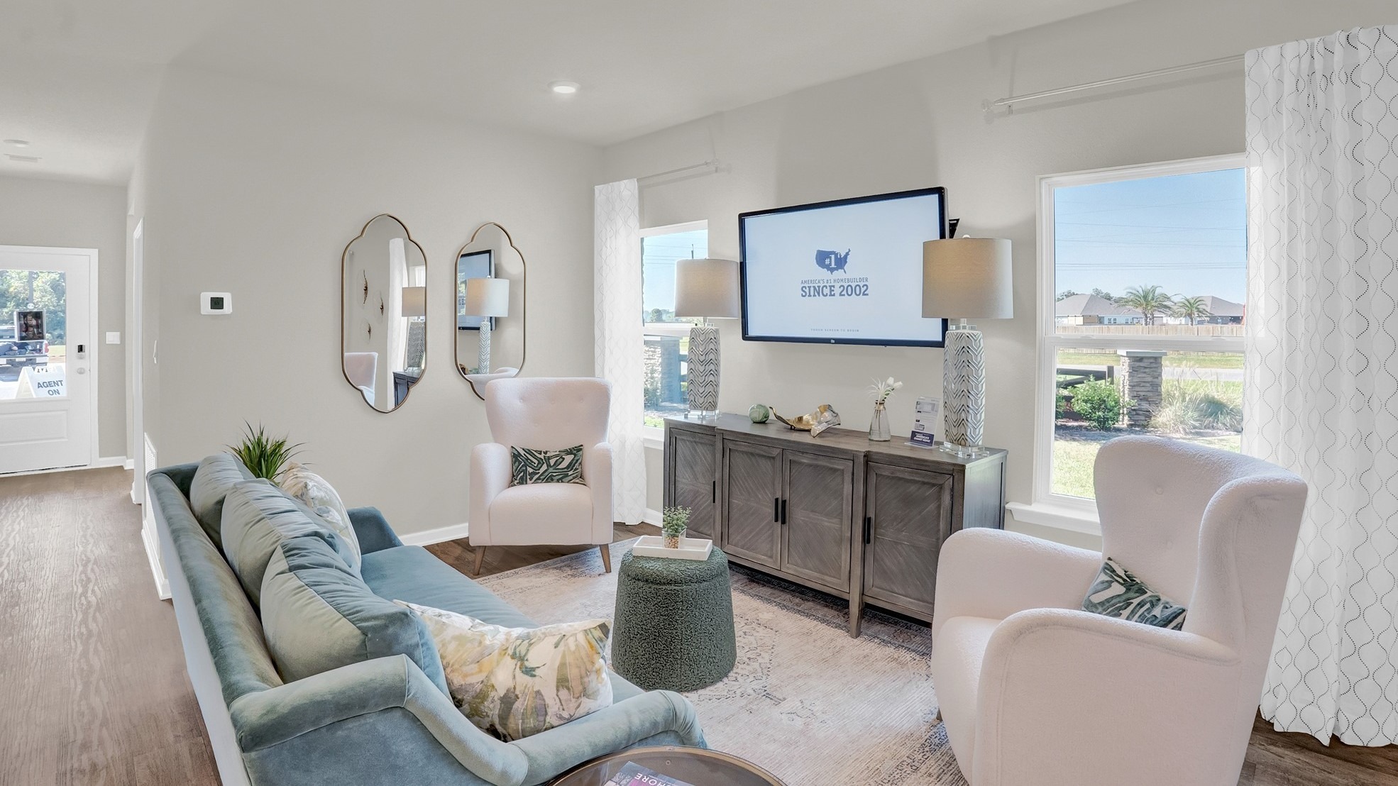 Living area with couch, chair and television on the wall.