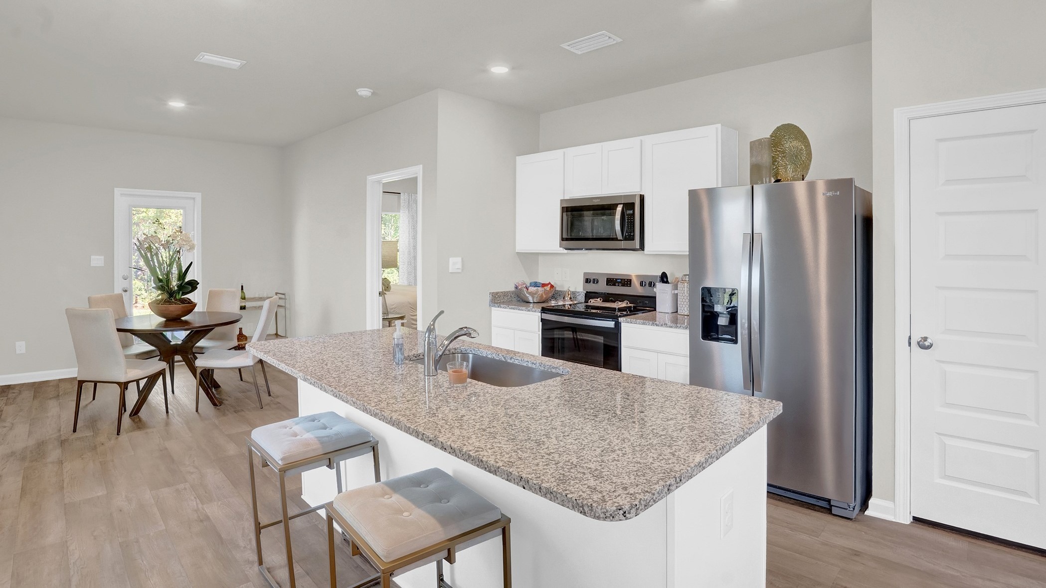 Kitchen with large island, backless chairs and stainless appliances.
