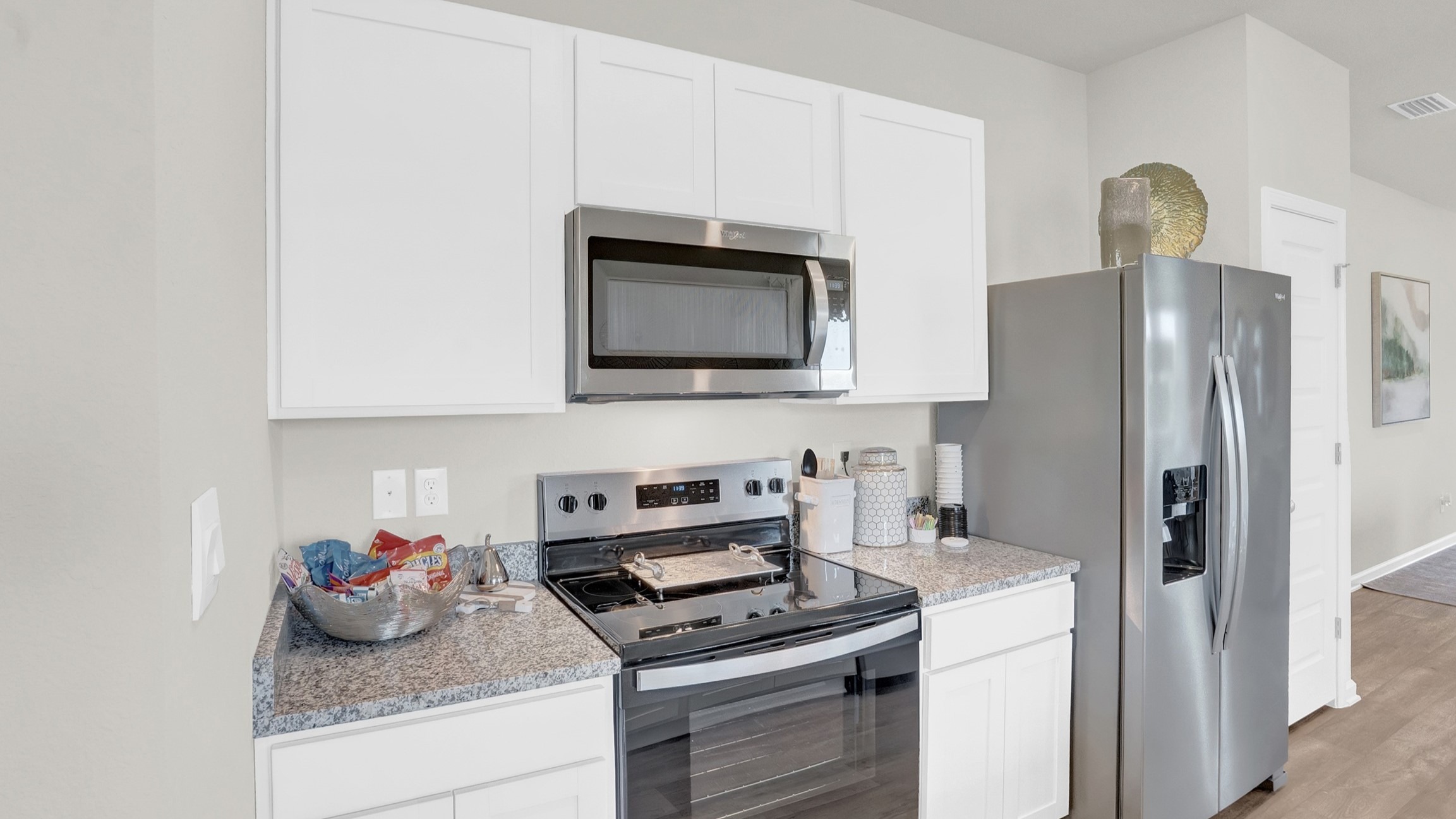 Kitchen area with stainless appliances and white cabinets..