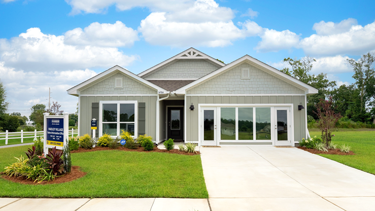 Single-story home with neutral-green board and batten and shake gable, a covered entryway, and a two-car garage.