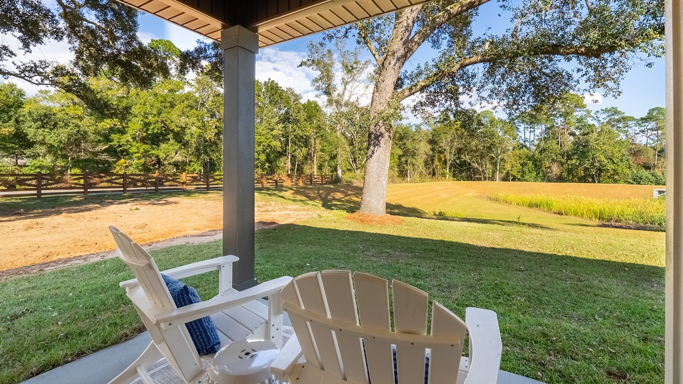 Covered rear patio overlooking pond in backyard.