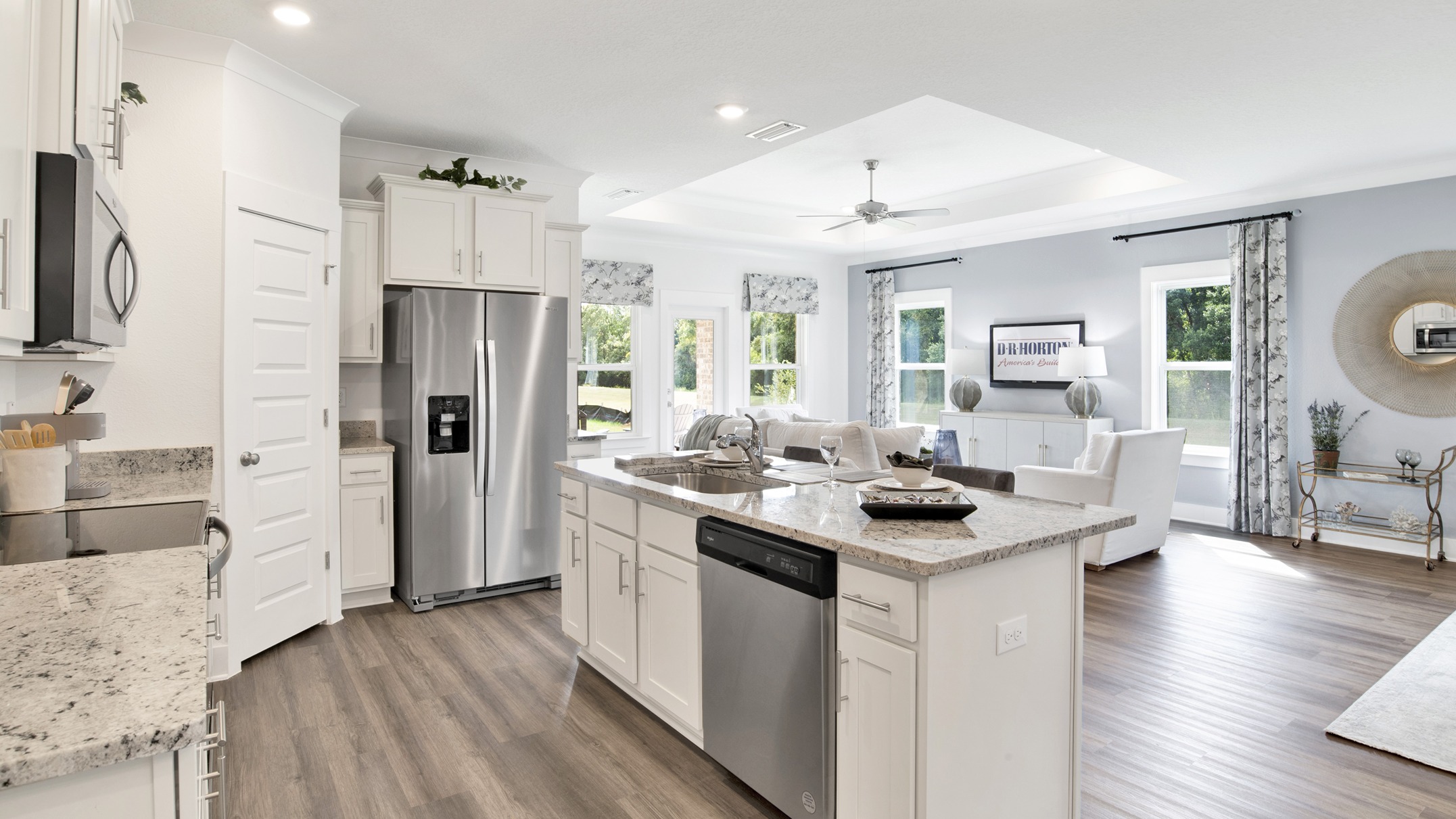 Open concept floorplan connecting kitchen, living room, and dining area with trey ceilings.
