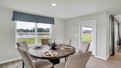 Dining area in kitchen by large window and glass door.