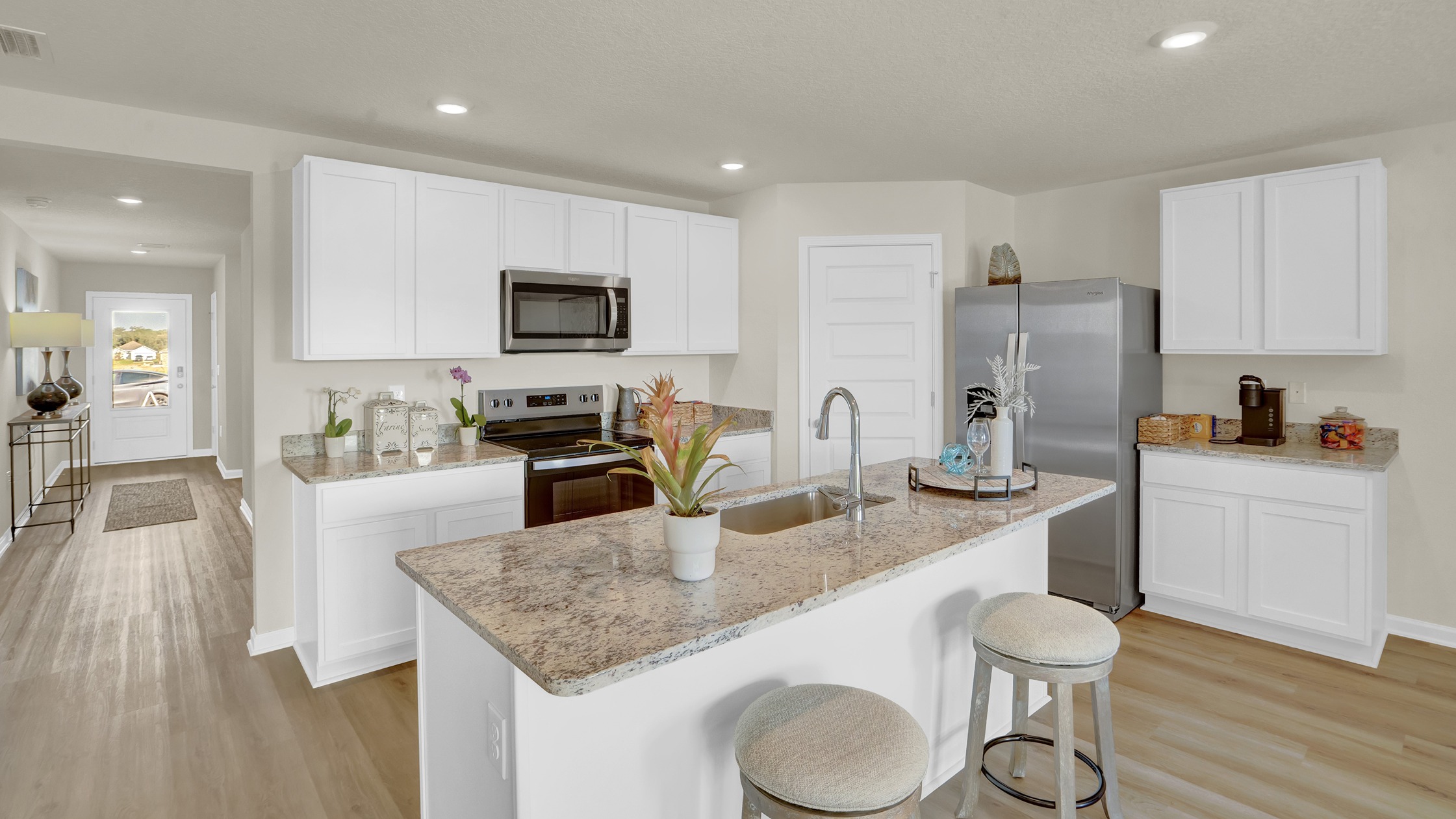 Cali floorplan kitchen with corner pantry and central island overlooking dining area and back porch access.