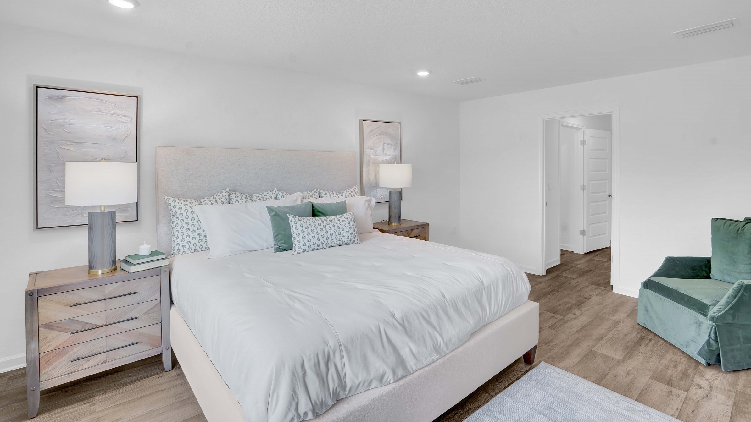 Ryder floor plan spacious primary bedroom with large bed, dresser, and accent chair.