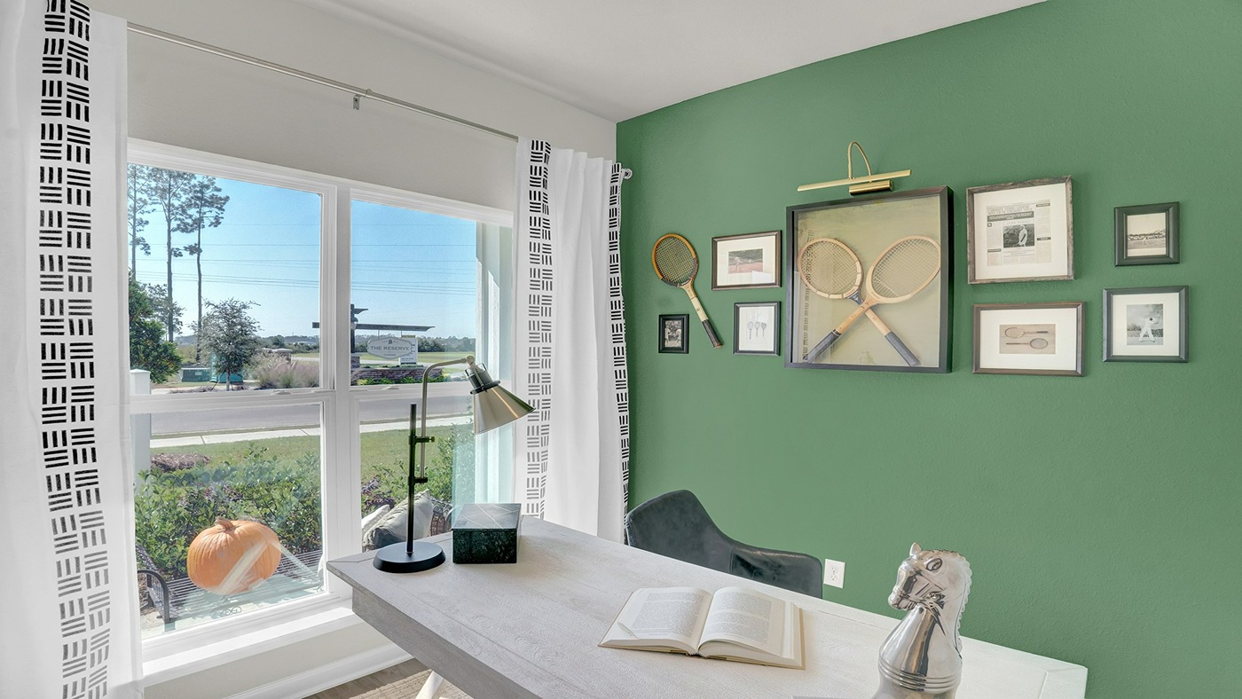 Office are with green walls, large window and desk.