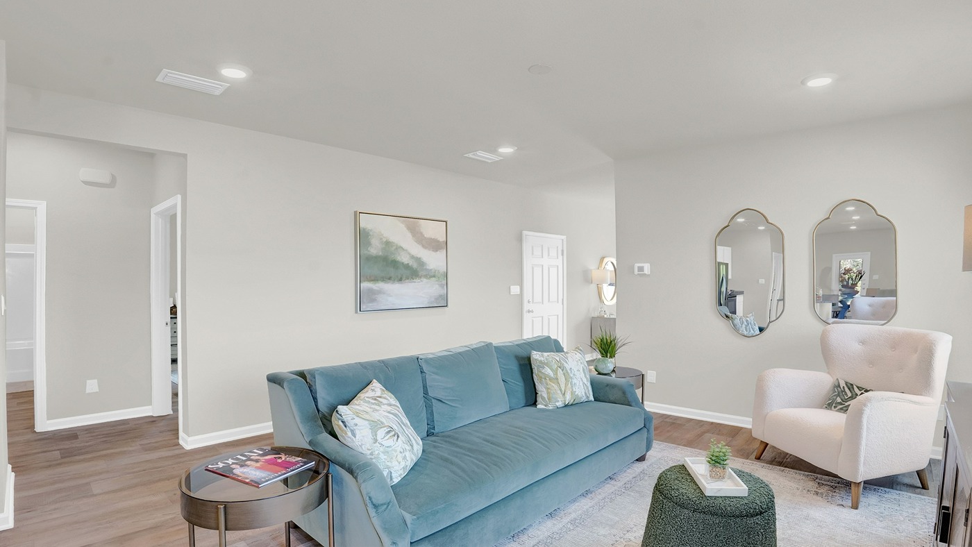 Living area with blue couch, white chairs and mirror art on the walls.