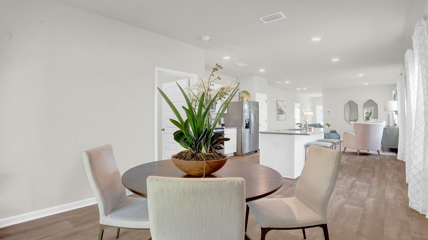 Breakfast area with round table and white chairs. Opens into the living area with white chair.