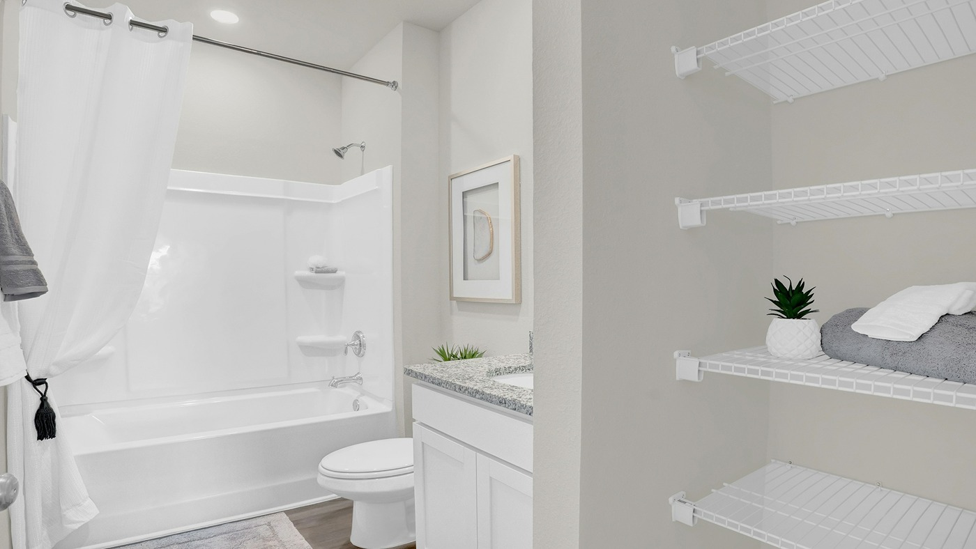 Bathroom with tub and shower combo with wire shelving.
