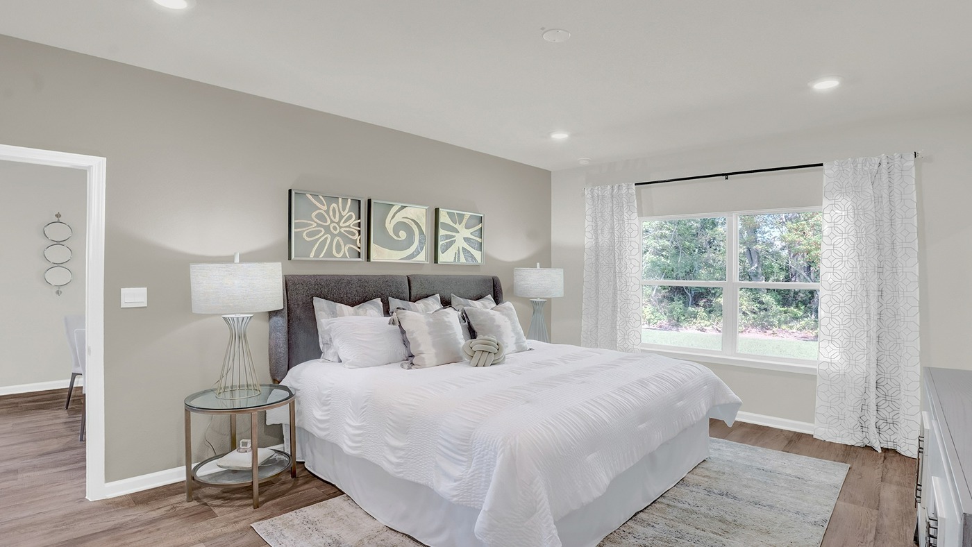 Bedroom with large bed, recessed lighting and windows showing natural light .