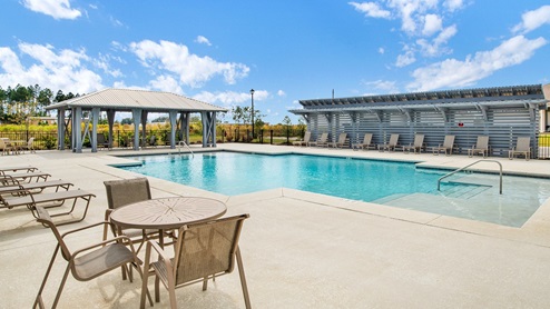Relaxing community pool with lounge chairs and a shaded cabana.