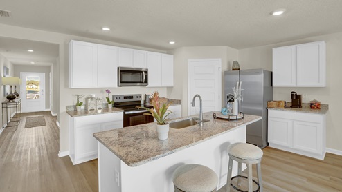 Kitchen peninsula with white cabinets, granite countertops, and stainless-steel appliances.