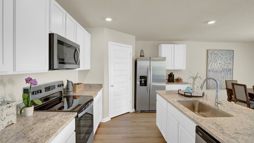Kitchen peninsula with white cabinets, granite countertops, and stainless-steel appliances.