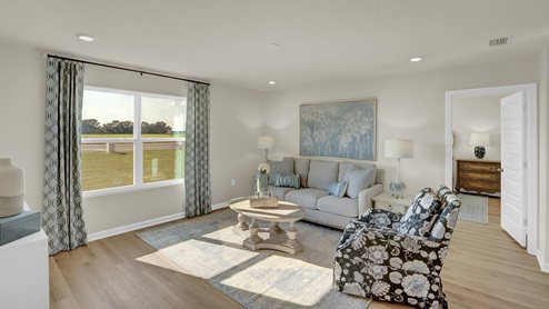 Spacious living room illuminated by natural light flowing in from large window.