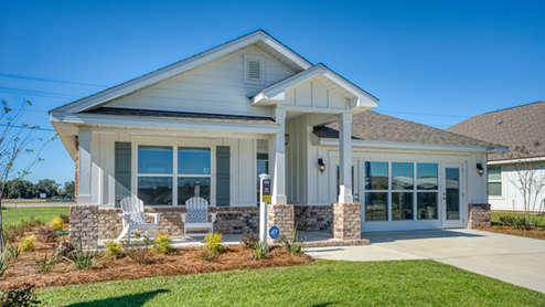 Single-story home with white board and batten, a brick water table, and two-car garage.