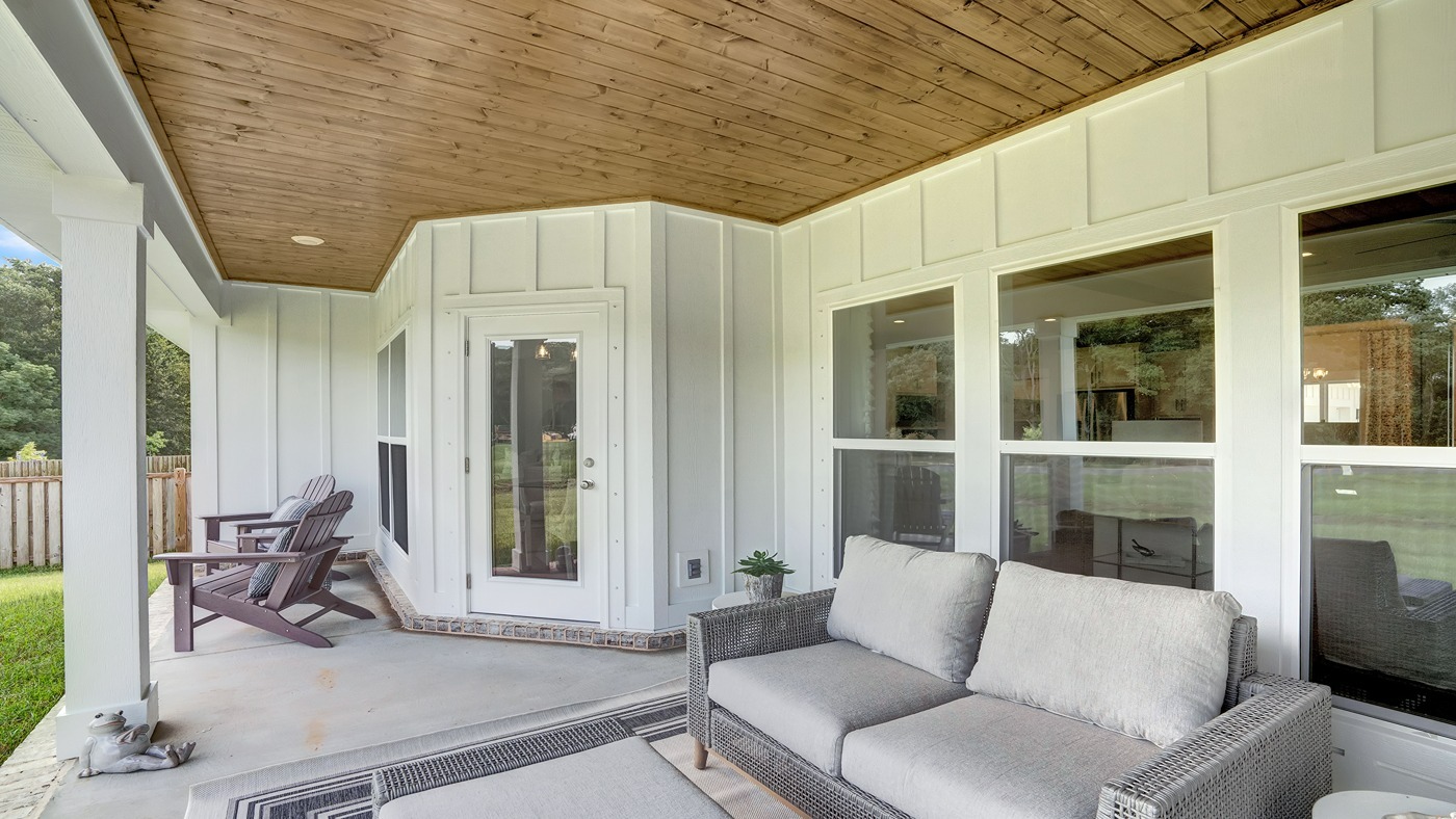 Gorgeous covered porch with white siding and natural wood under covered roof area.