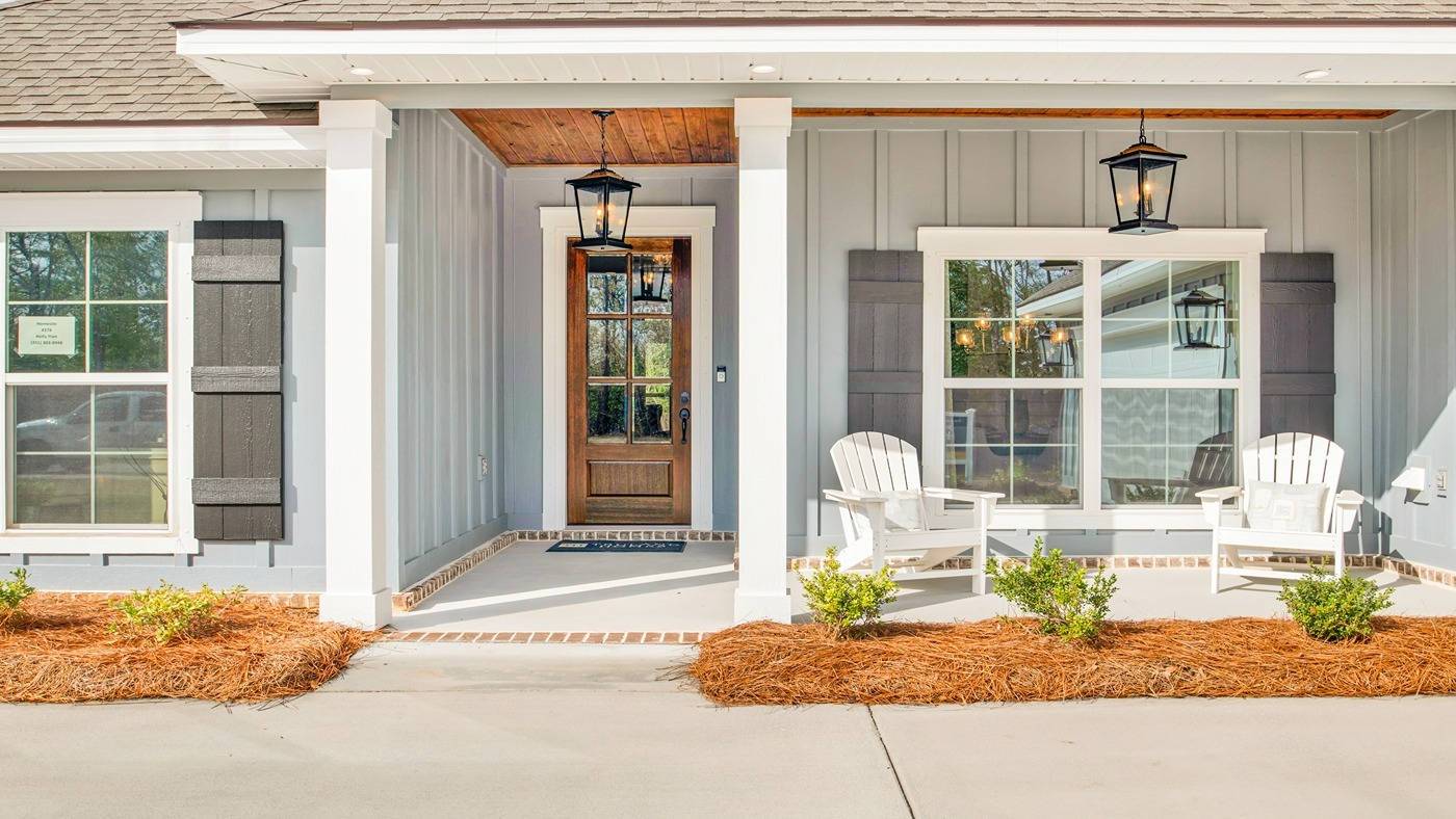 Front porch with siding and beautiful door, windows with shutters and accent lighting.