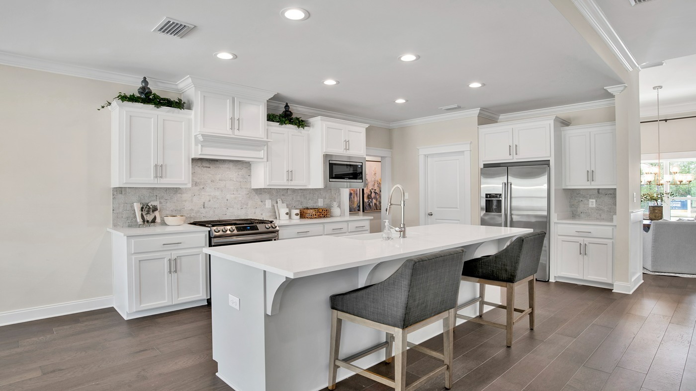 Kitchen with modern lighting and appliances and white cabinets.
