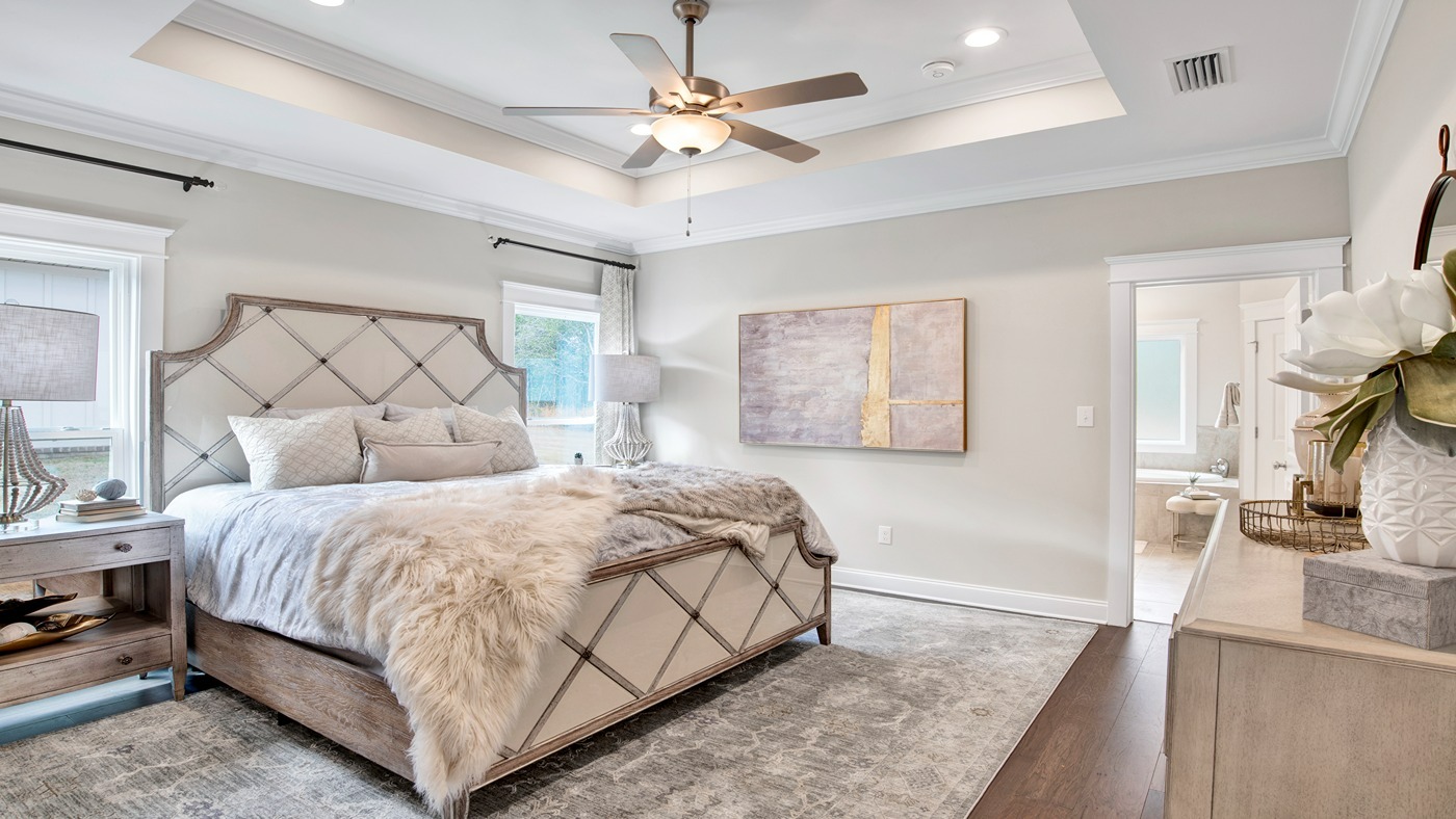 Master bedroom with tray ceiling and large windows.