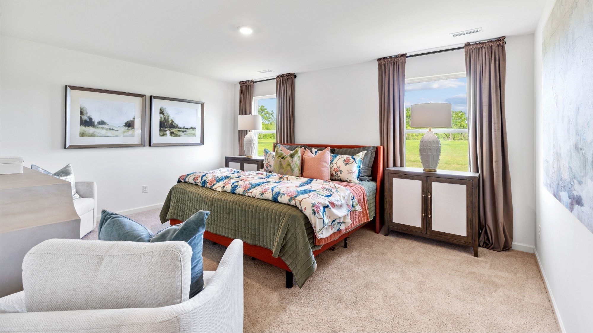 Primary bedroom with light-colored carpet, a King sized bedframe, and 2 accent chairs.