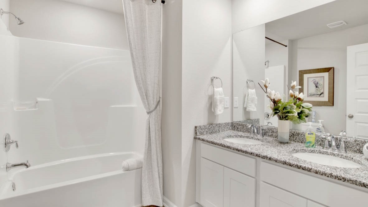 Spare bathroom with dual sink vanities, granite countertops, and a shower/bathtub combination.