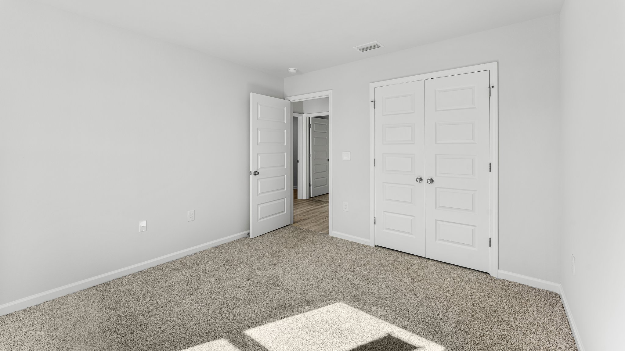 Spare bedroom with light-colored carpet.