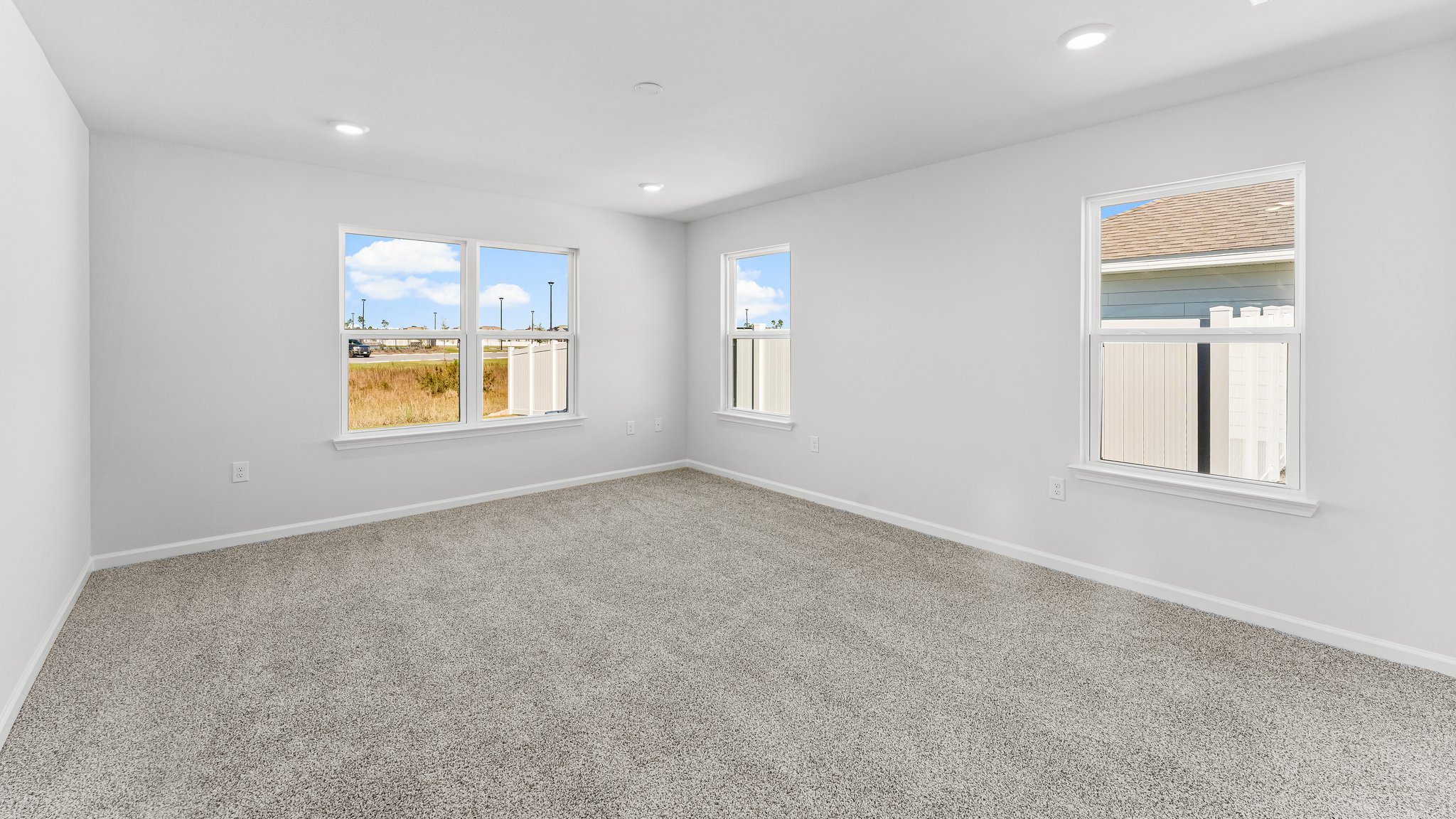 Spacious primary bedroom with light-colored carpets and large windows.