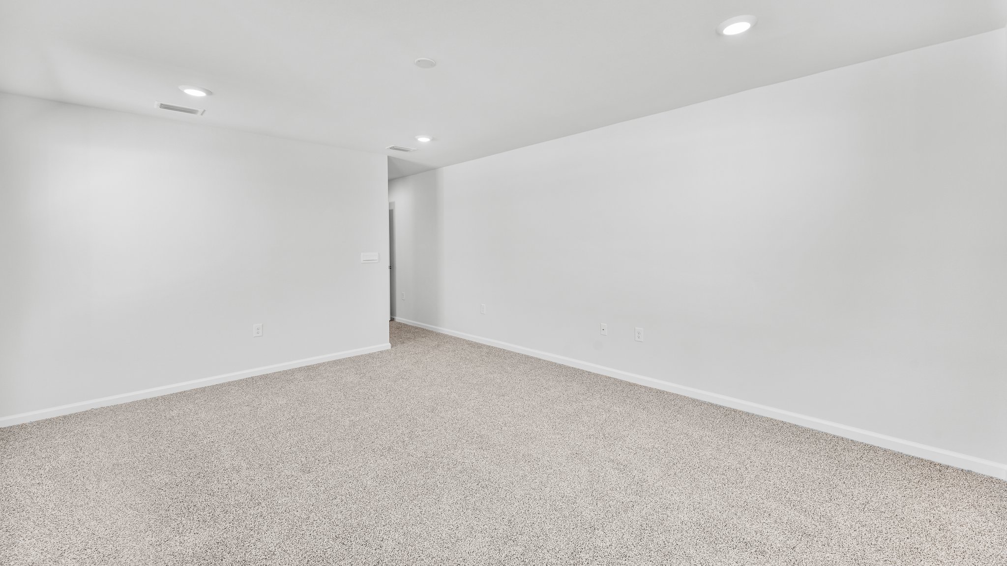 Spacious primary bedroom with light-colored carpets and large windows.