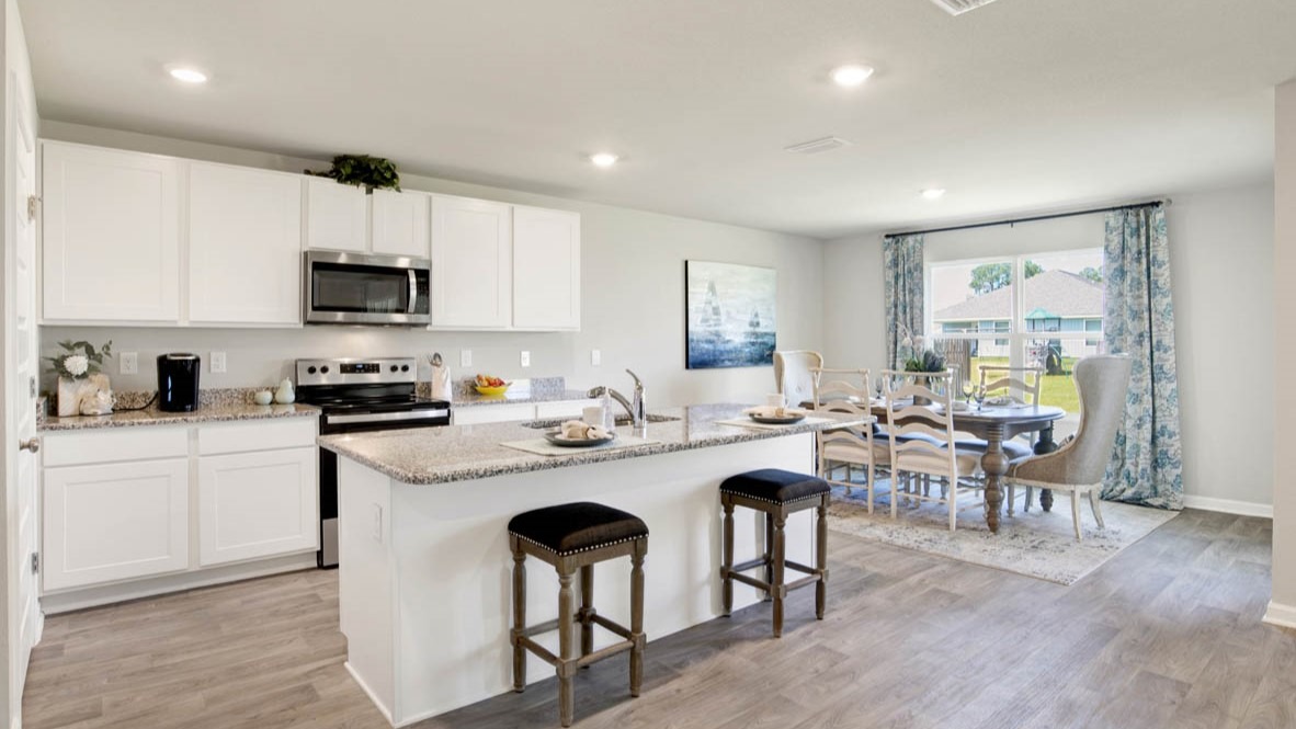 Spacious kitchen with a peninsula island, shaker-style cabinetry, stone countertops, and stainless-steel appliances.