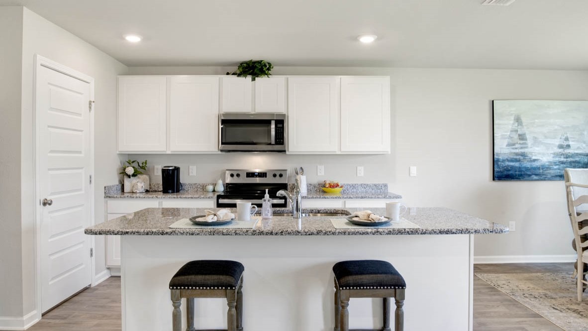 Spacious kitchen with a peninsula island, shaker-style cabinetry, stone countertops, and stainless-steel appliances.