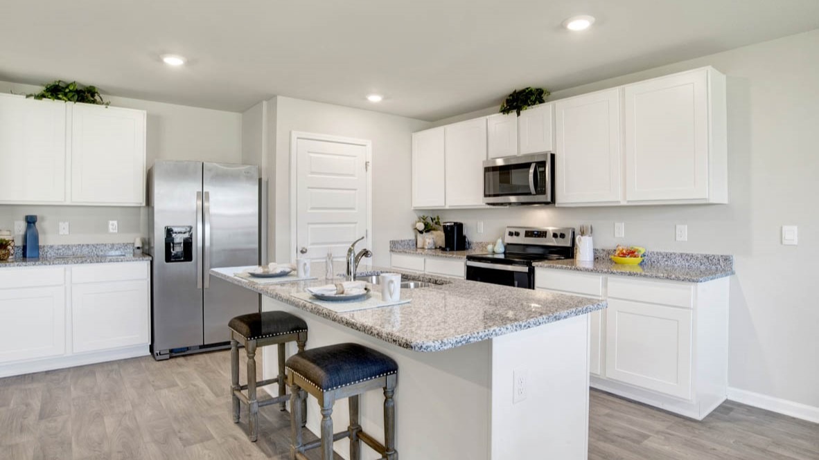 Spacious kitchen with a peninsula island, shaker-style cabinetry, stone countertops, and stainless-steel appliances.