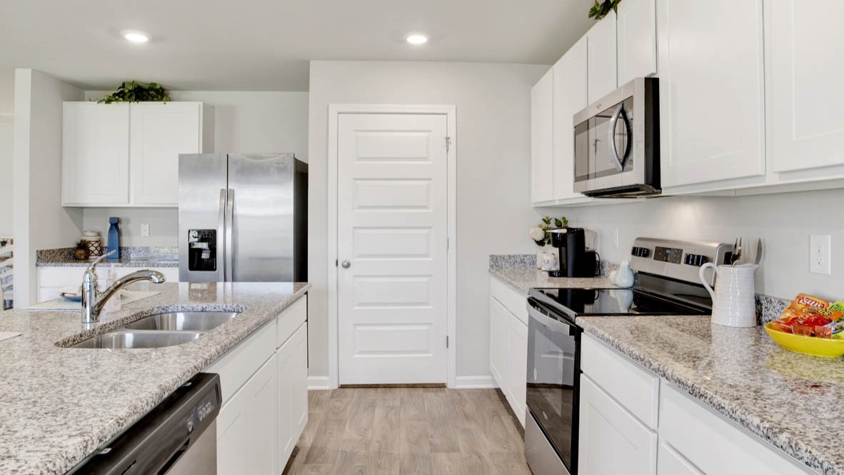 Kitchen with large central peninsula, shaker-style cabinetry, granite countertops, and stainless-steel appliances.
