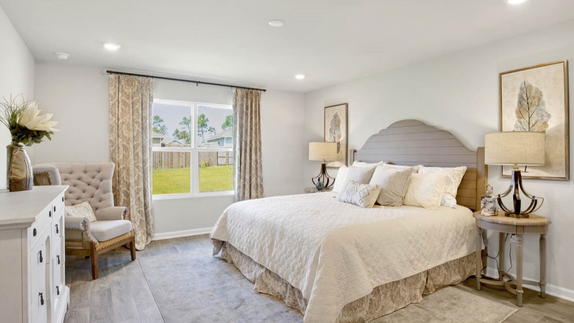 Spacious primary bedroom with light-colored carpet and a king-size bedframe.
