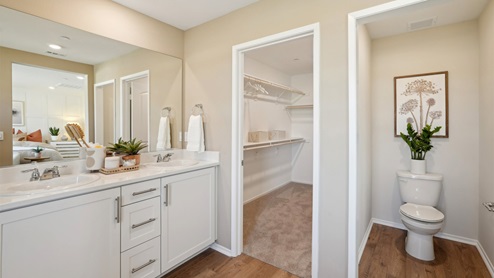 Primary bathroom with dual vanities and walk-in closet